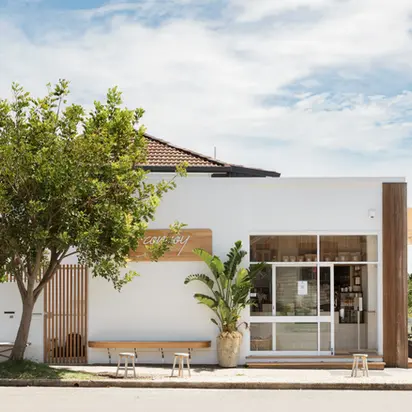 Modern white cafe with outdoor benches and tree