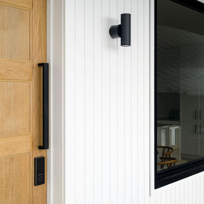 Modern white exterior, natural wood door, black handle, outdoor light, window.